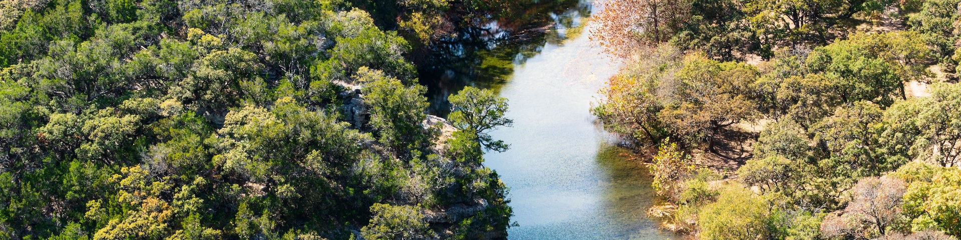 A river winding through a dense forest with rocky outcrops.