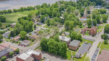 An aerial view of a town with a river, green fields, and a large building with a dome.
