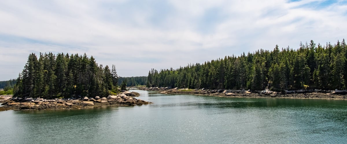 A calm lake surrounded by dense forests and rocky shores.