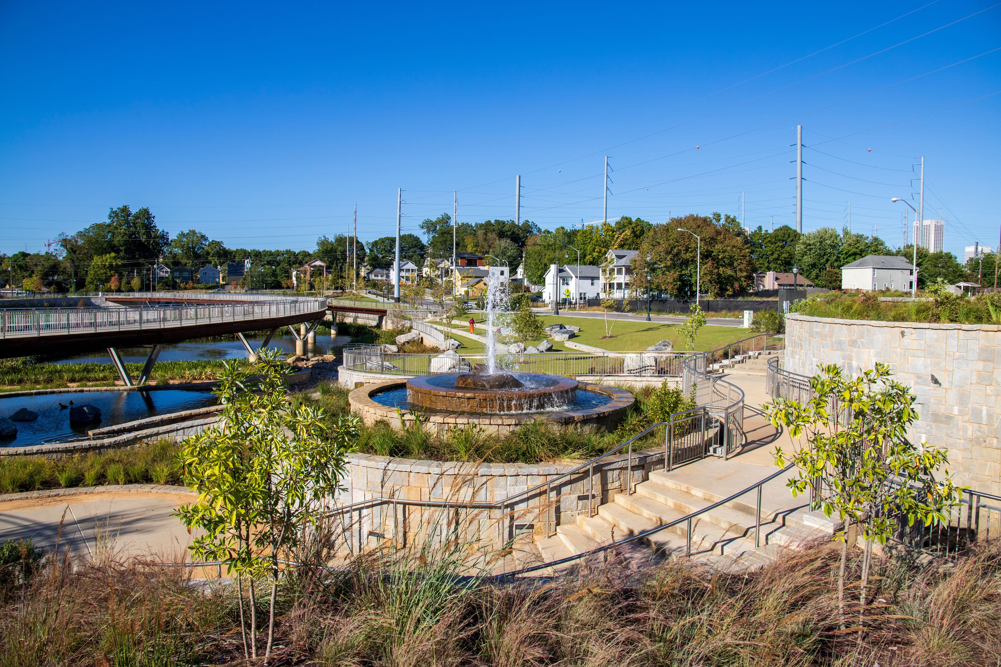 a gorgeous autumn landscape at Rodney Cook Sr. Park in Historic Vine City with water fountains surrounded by lush green trees, grass and plants with a gorgeous blue sky in Atlanta Georgia USA
