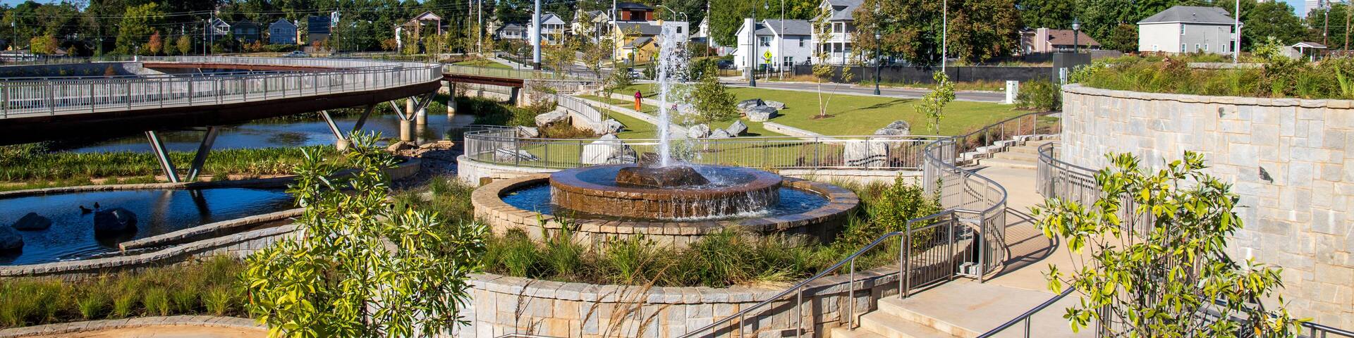 a gorgeous autumn landscape at Rodney Cook Sr. Park in Historic Vine City with water fountains surrounded by lush green trees, grass and plants with a gorgeous blue sky in Atlanta Georgia USA