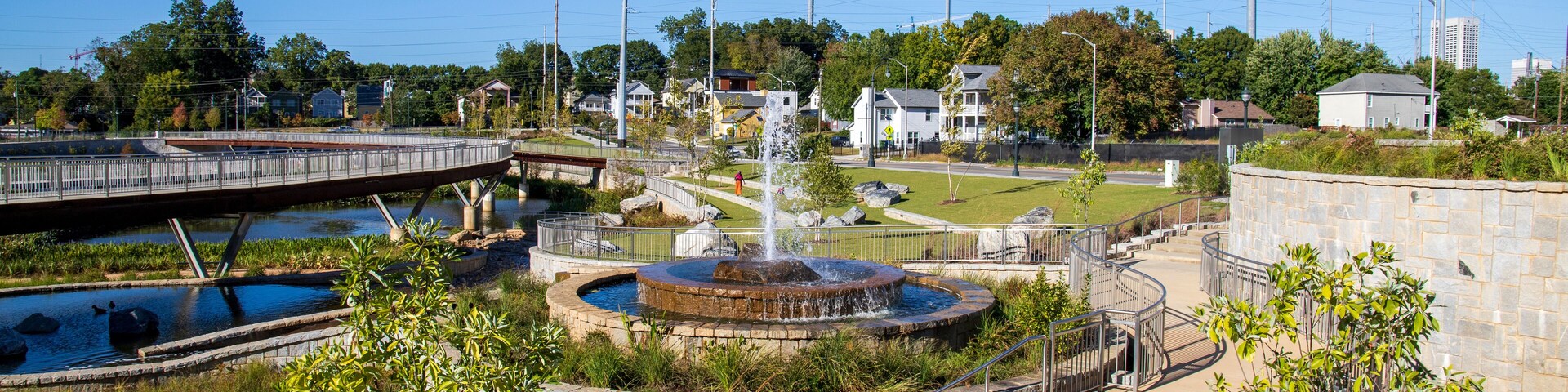 a gorgeous autumn landscape at Rodney Cook Sr. Park in Historic Vine City with water fountains surrounded by lush green trees, grass and plants with a gorgeous blue sky in Atlanta Georgia USA