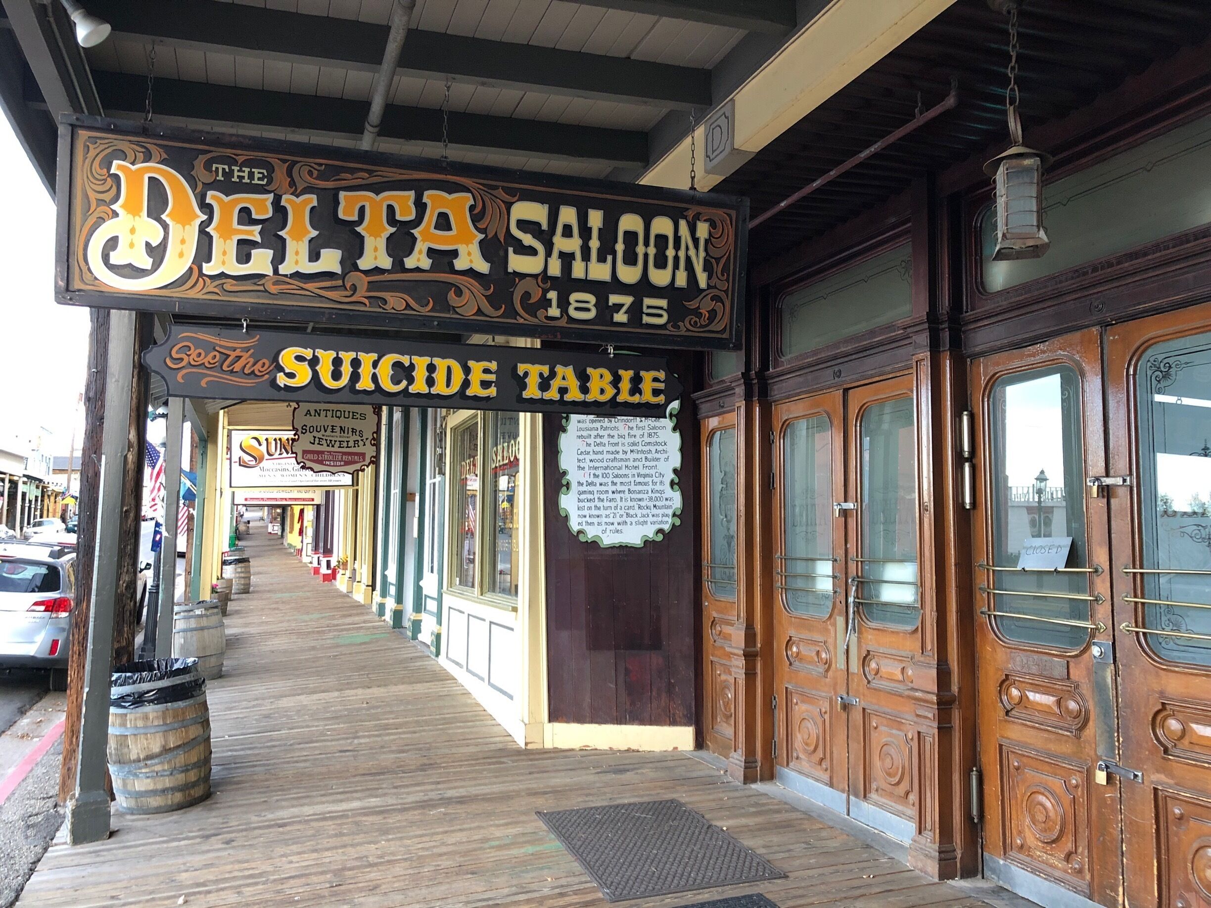Una pasarela de madera con un saloon llamado "The Delta Saloon 1875" y un letrero que dice "Suicide Table".
