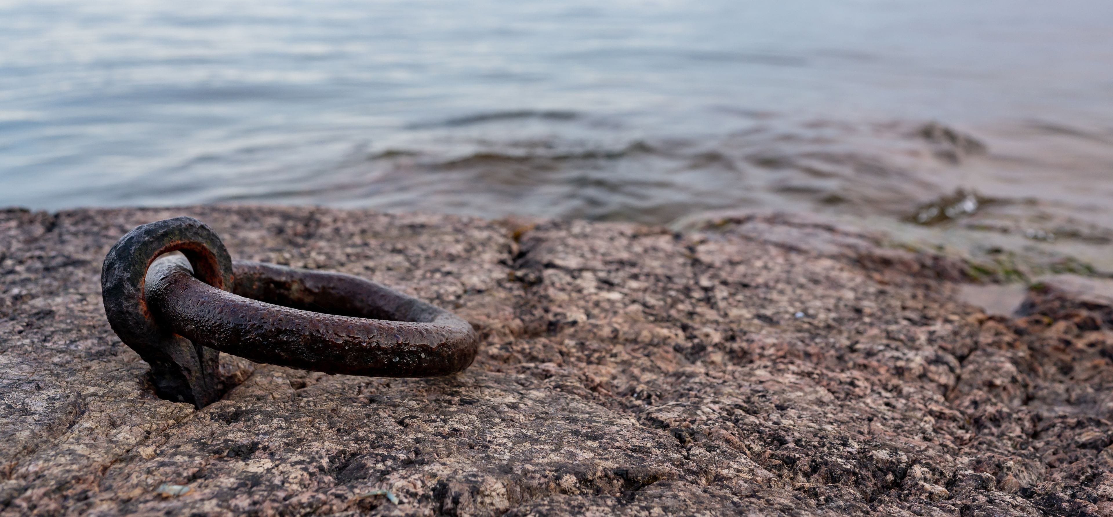 Old rusty mooring ring in rock near lake Vattern Motala Sweden