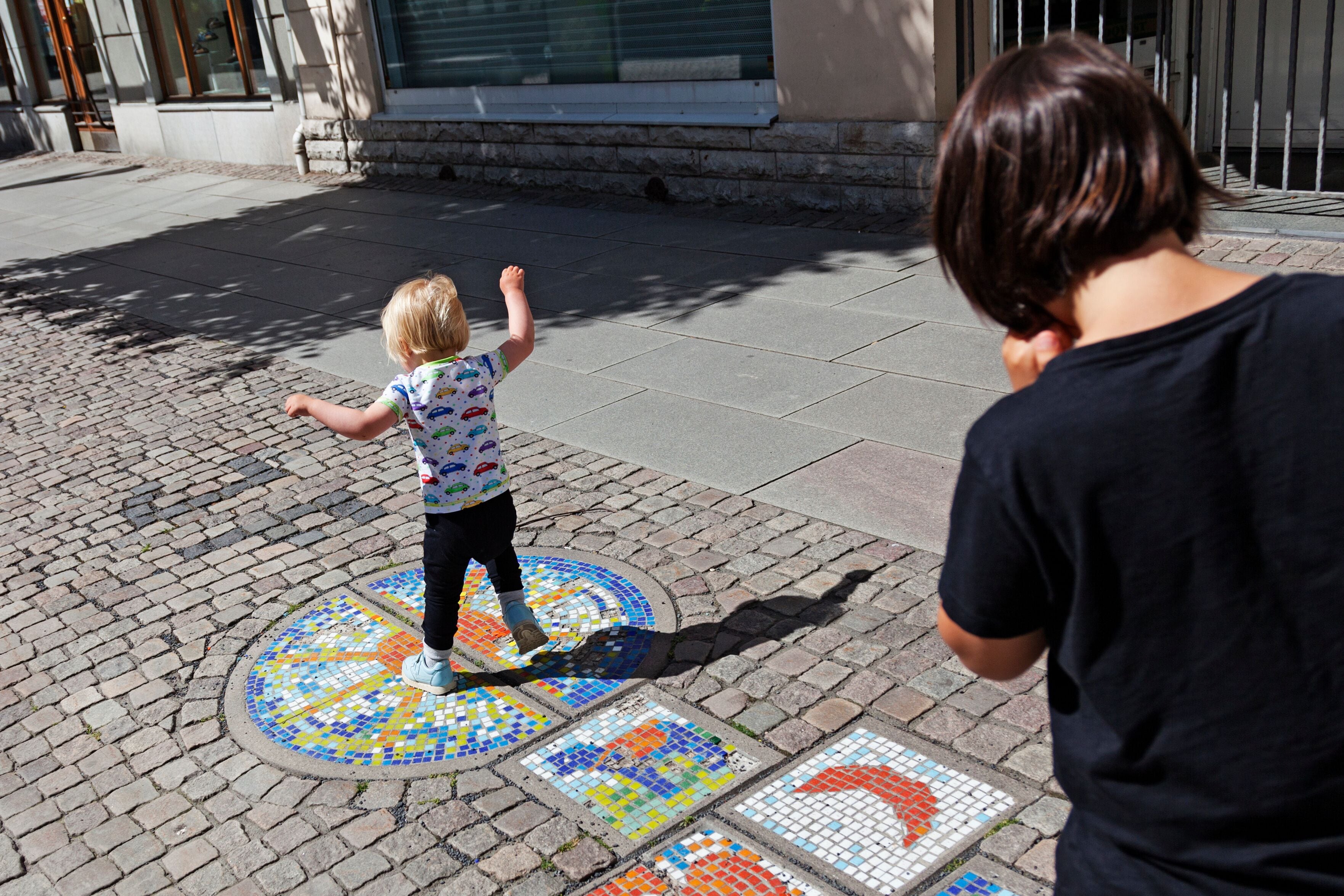 Un niño jugando en un pavimento con un diseño de mosaico.