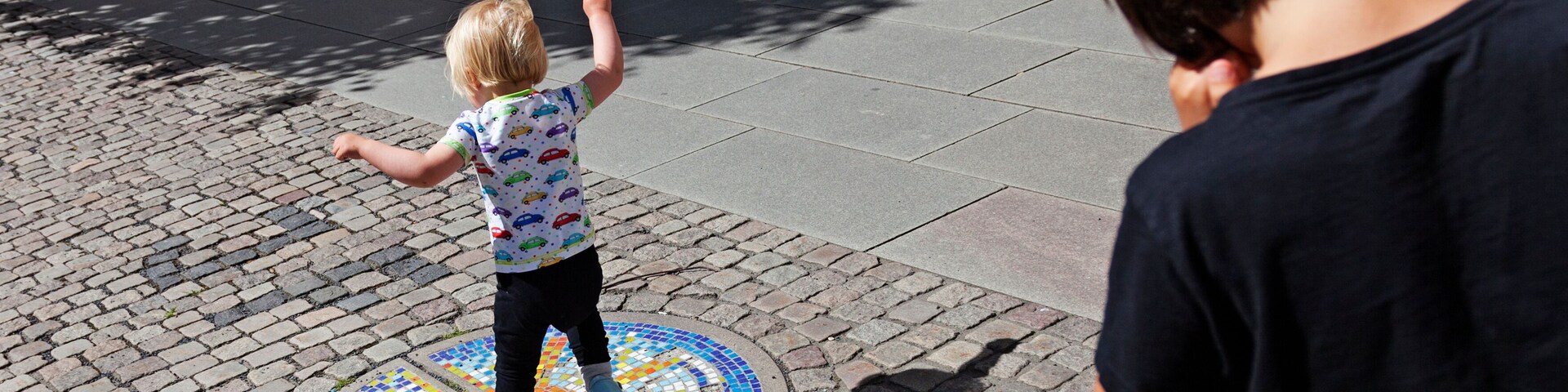 Un niño jugando en un pavimento con un diseño de mosaico.