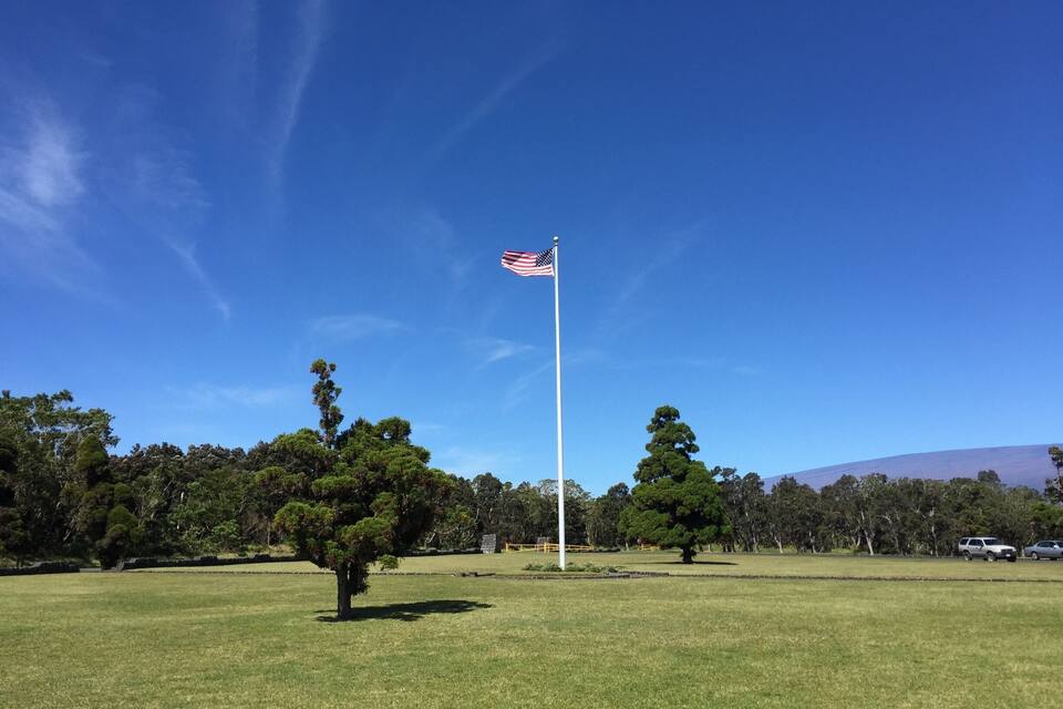 A grassy field with a flagpole and an American flag.