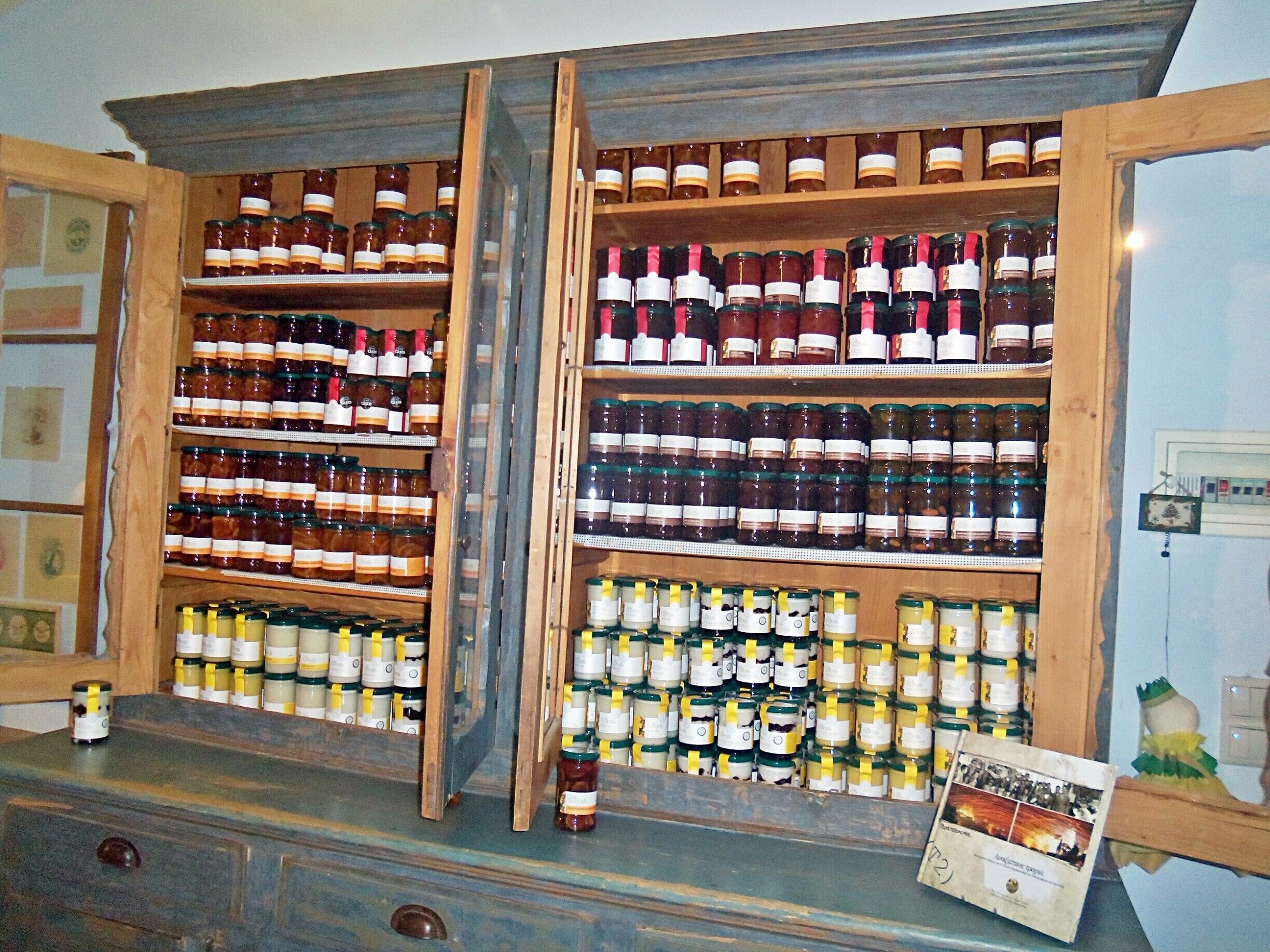 A wooden cabinet filled with various bottles of honey and other preserves.