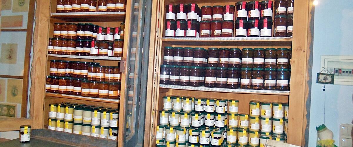 A wooden cabinet filled with various bottles of honey and other preserves.