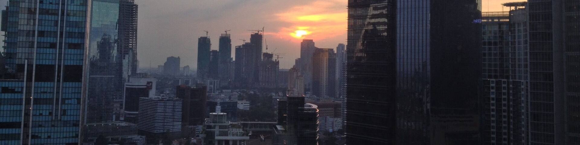 A cityscape with modern skyscrapers and a sunset in the background.