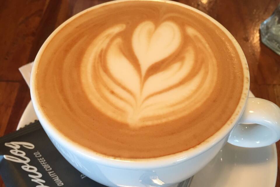 Uma chávena de café com arte de latte num pires.