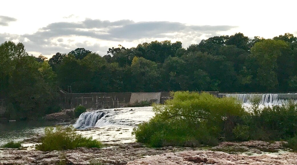 One of Missouri’s least-talked-about wonders is located on Shoal Creek, just south of Joplin. Grand Falls, Missouri’s largest natural, continually flowing waterfall, is like a miniature Niagara Falls. On a breezy day, you’ll feel the mist hit your face. It’s exhilarating to find a natural, beautiful spot such as this on a warm summer day in the Missouri Ozarks.
You can climb down a bit of umber-colored chert, also known as flint, as you head toward this scenic stop. One of the widest waterfalls in the state, Grand Falls is caused by unusually thick layers of chert rock.
Although Missouri does have higher waterfalls, they don’t flow all year like Grand Falls. During high water, the height of the falls increases to roughly 25 feet.
As you walk toward Grand Falls, be sure to take in the beauty of the rock formations. The chert is often pocked with pools of water, making tiny natural swimming pools for frogs or small plants to grow and abide.
To reach the falls from the junction of Interstate 44 and Highway 86, go south one mile, cross Shoal Creek and turn right immediately after crossing the bridge. Follow the drive along the south bank of Shoal Creek for three more miles. Be on the lookout for the falls on your right. The approach from the north side is on private property.