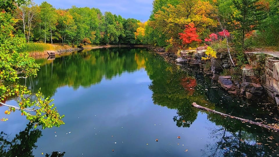 A calm river with reflections of trees and a clear sky.