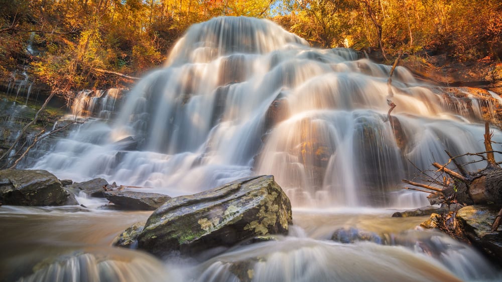 Une cascade Ă plusieurs niveaux, entourĂ©e dâarbres aux couleurs automnales.