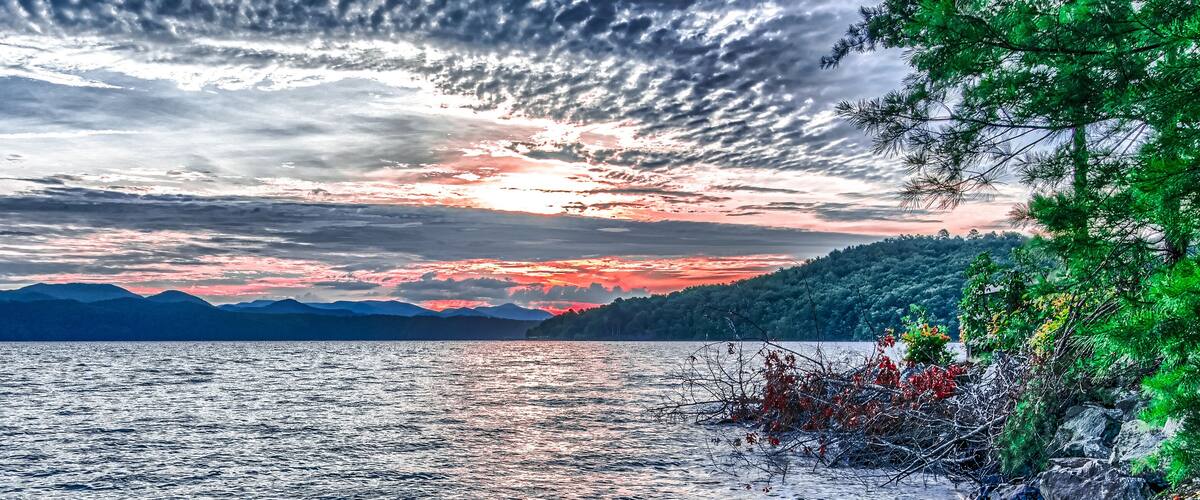 A lake with mountains in the background and a sunset sky.