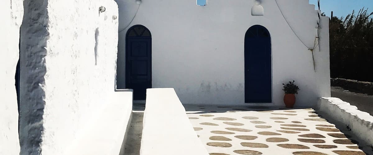 A white church with two bell towers, a blue door, and a flag.