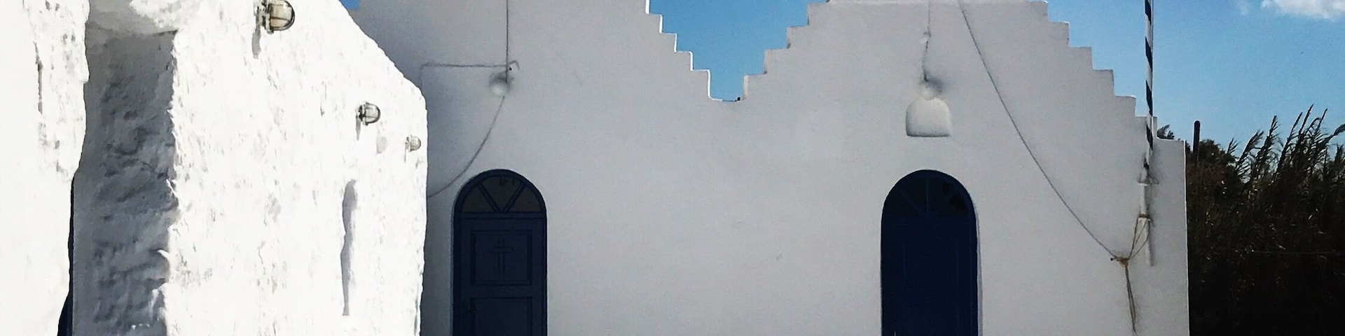 A white church with two bell towers, a blue door, and a flag.