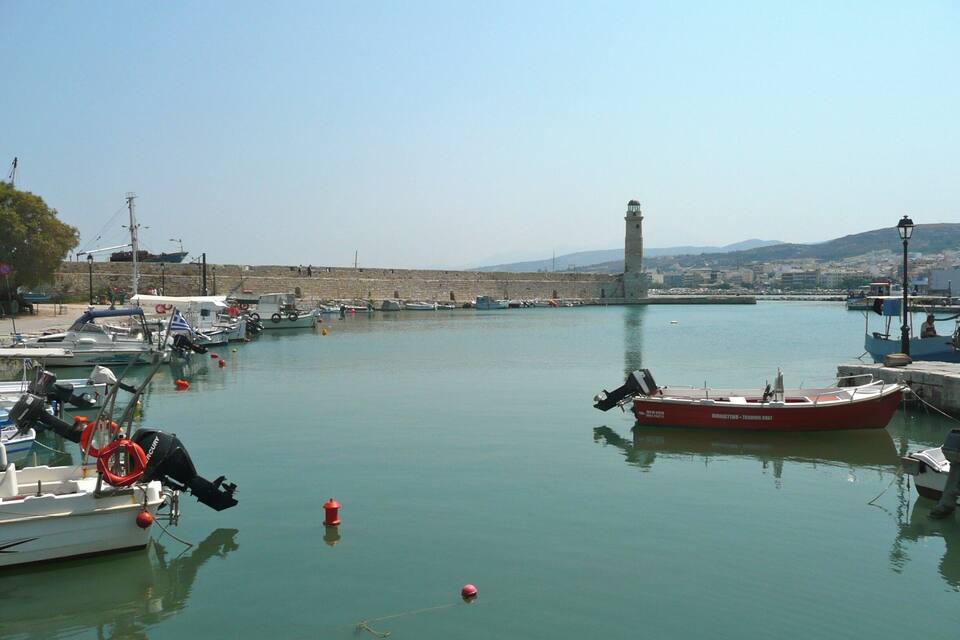 A harbor with boats, a lighthouse, and a stone wall.