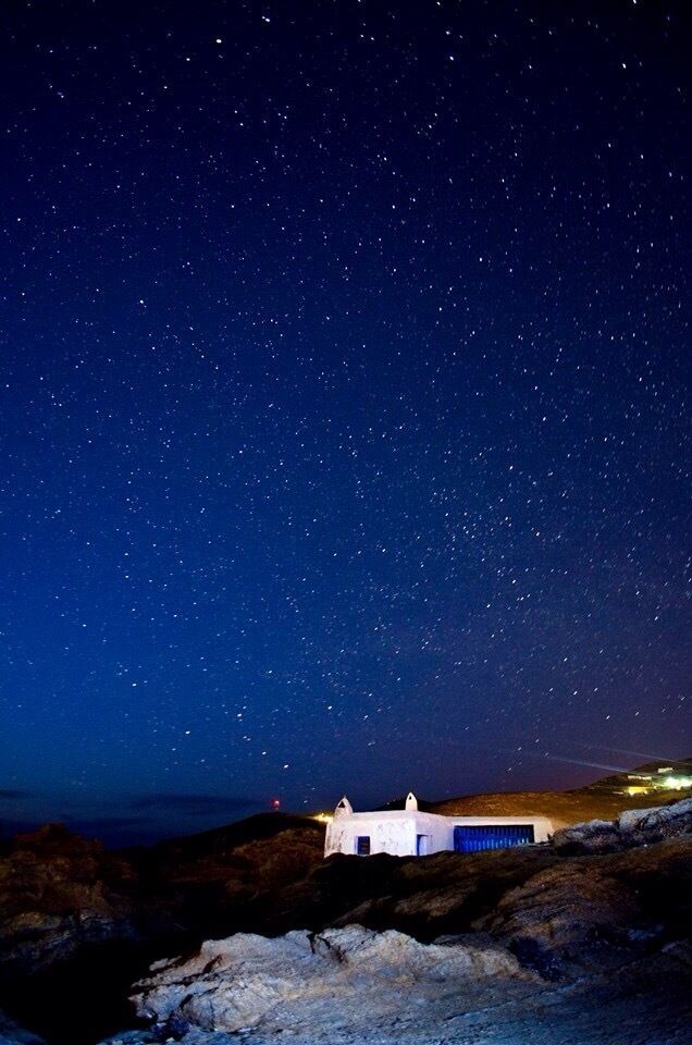 A white building with a blue roof under a starry night sky.