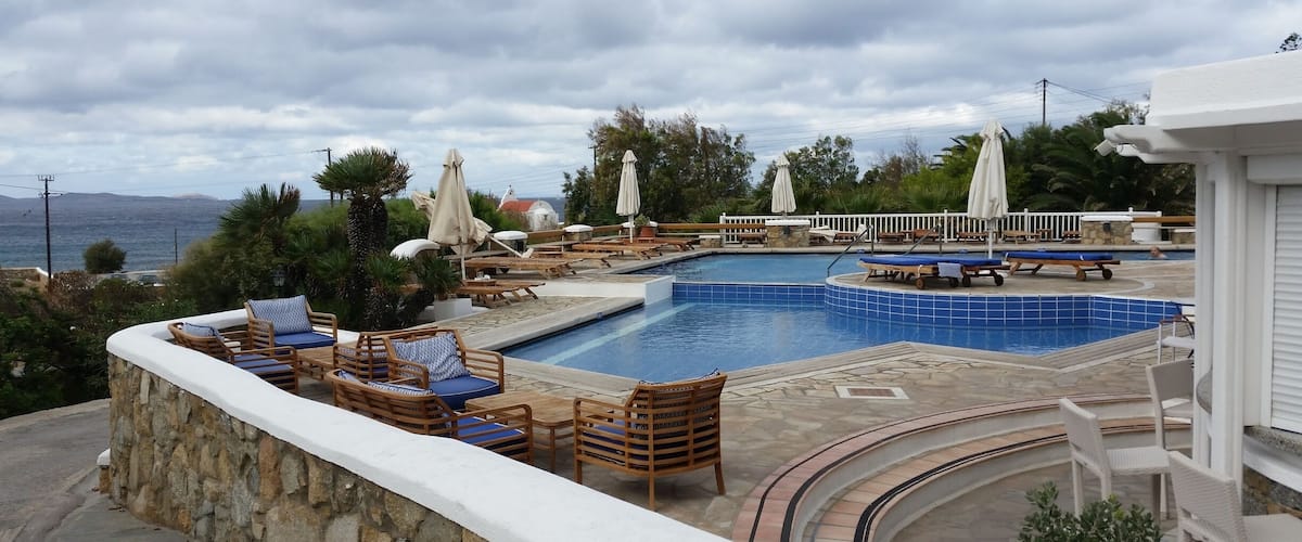 A pool area with lounge chairs and umbrellas, overlooking a body of water.