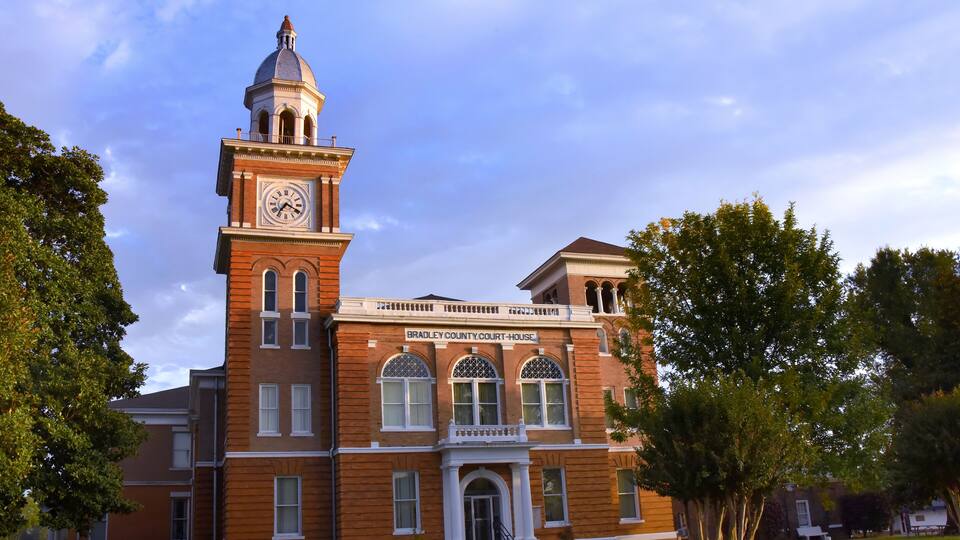 A brick courthouse with a clock tower and arched windows.