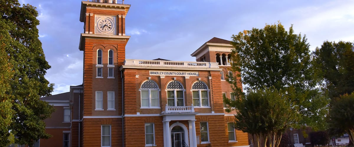 A brick courthouse with a clock tower and arched windows.