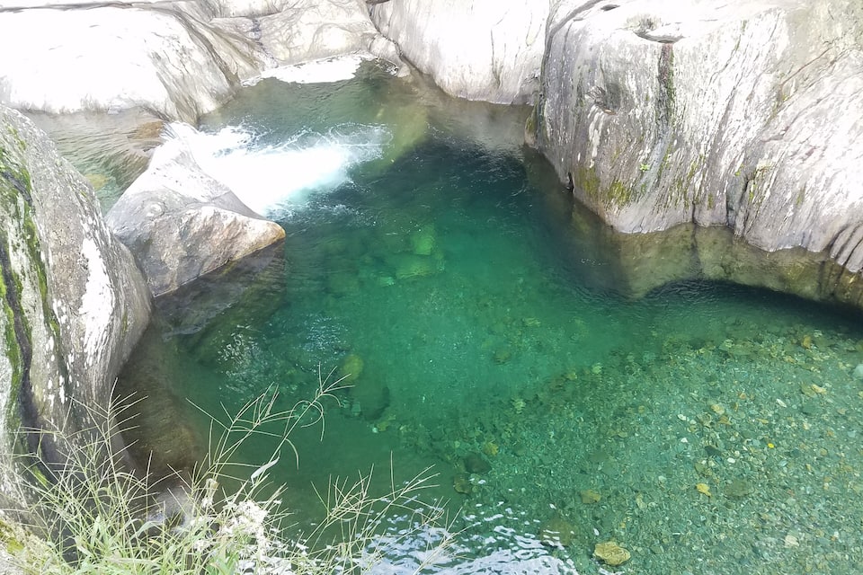 A clear, greenish pool surrounded by rocky terrain.