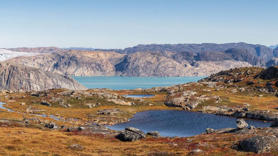 A mountainous landscape with a lake and a glacier in the background.