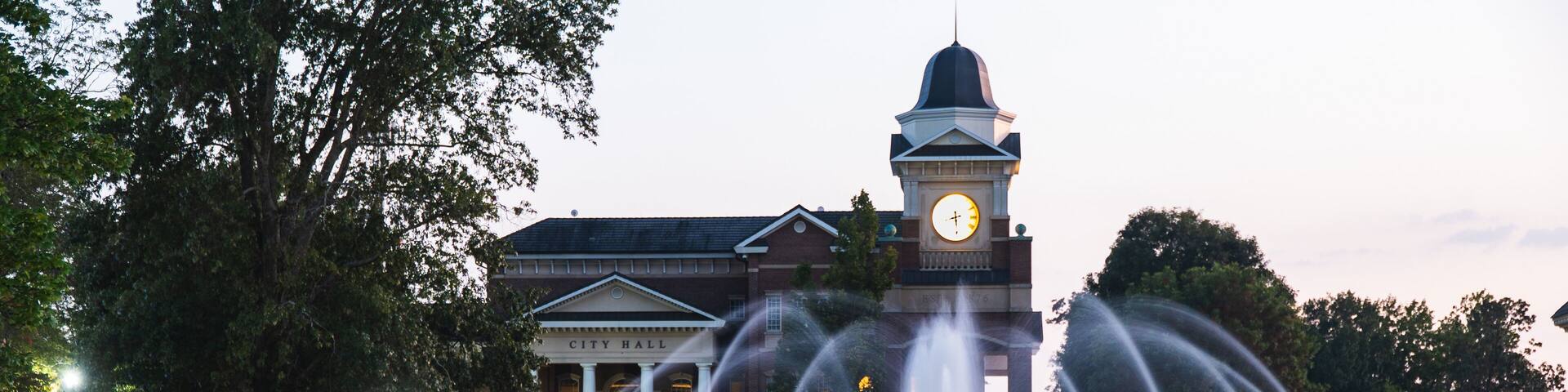 An illuminated view of Town Hall in City of Duluth in Georgia shot during sunset with fountains in the foreground.