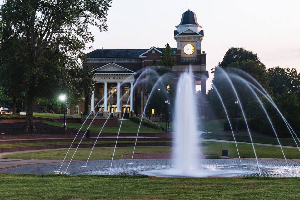A fountain in front of a building with a clock tower.
