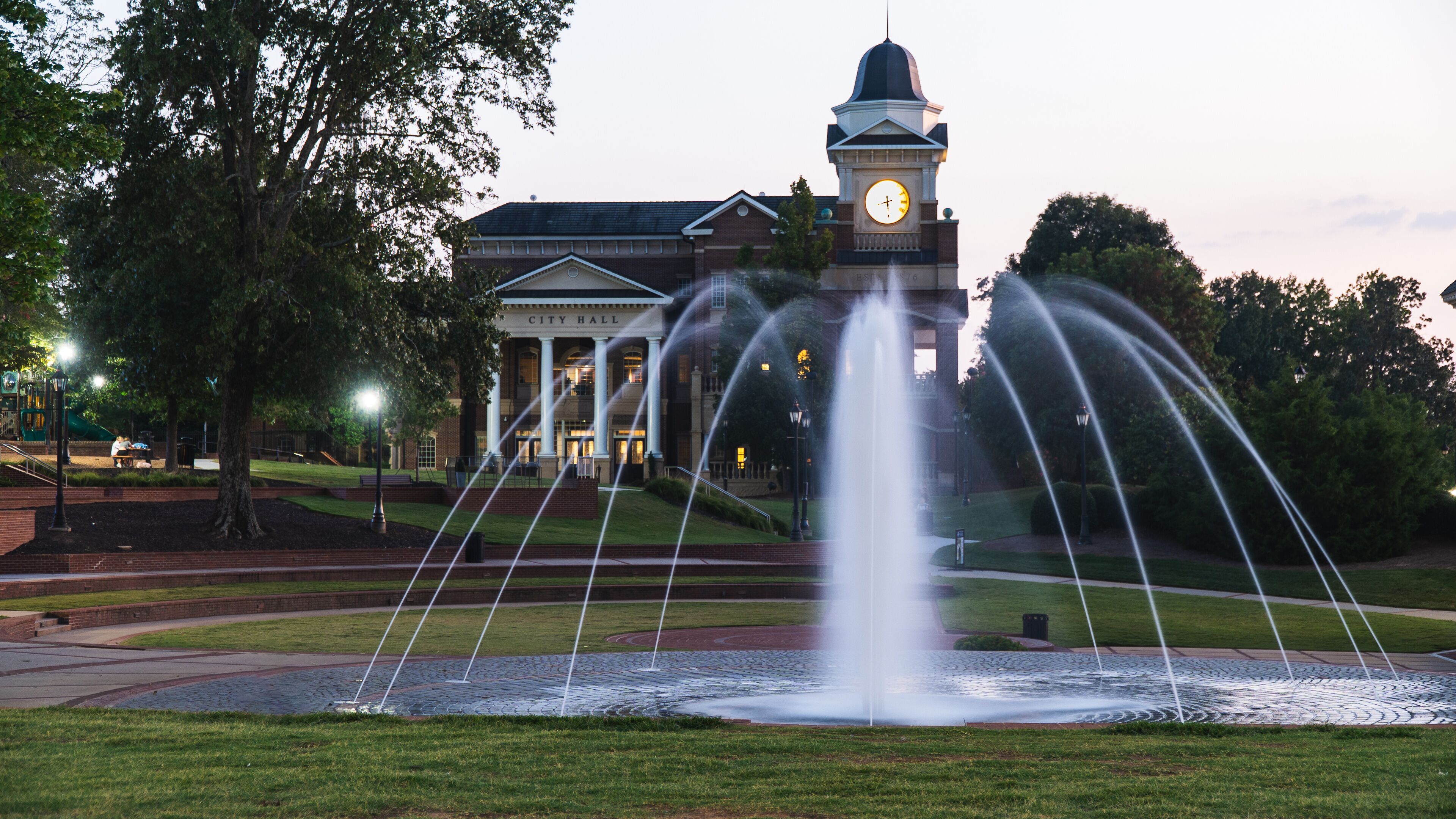 A fountain in front of a building with a clock tower.