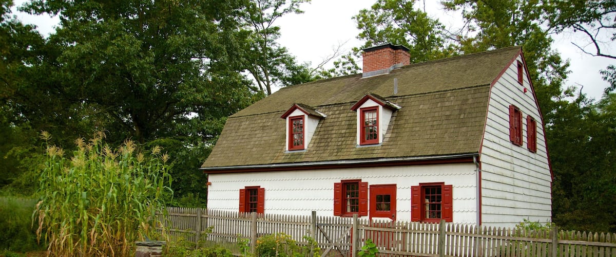 A white house with red shutters and a wooden fence.