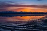 Un coucher de soleil sur une chaîne de montagnes se reflétant dans un lac paisible.