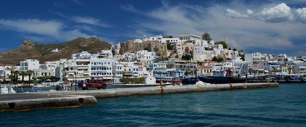 A coastal town with white buildings, a mountain, and boats in the harbor.
