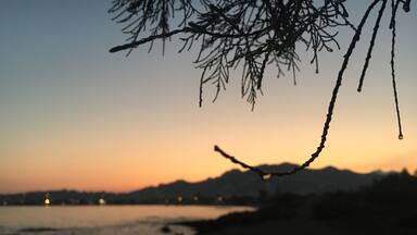 A sunset over a beach with silhouettes of mountains in the background.
