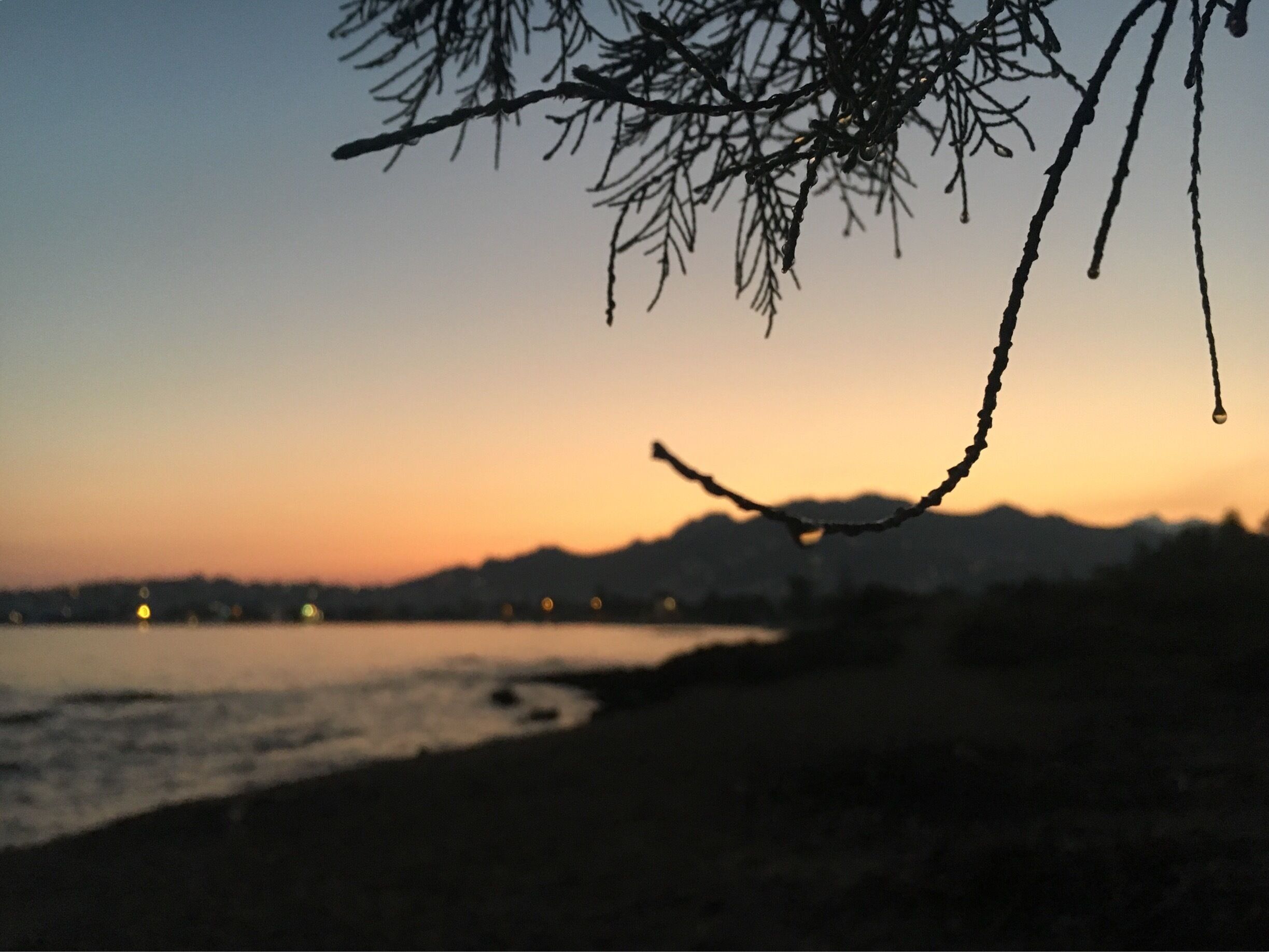 A sunset over a beach with silhouettes of mountains in the background.