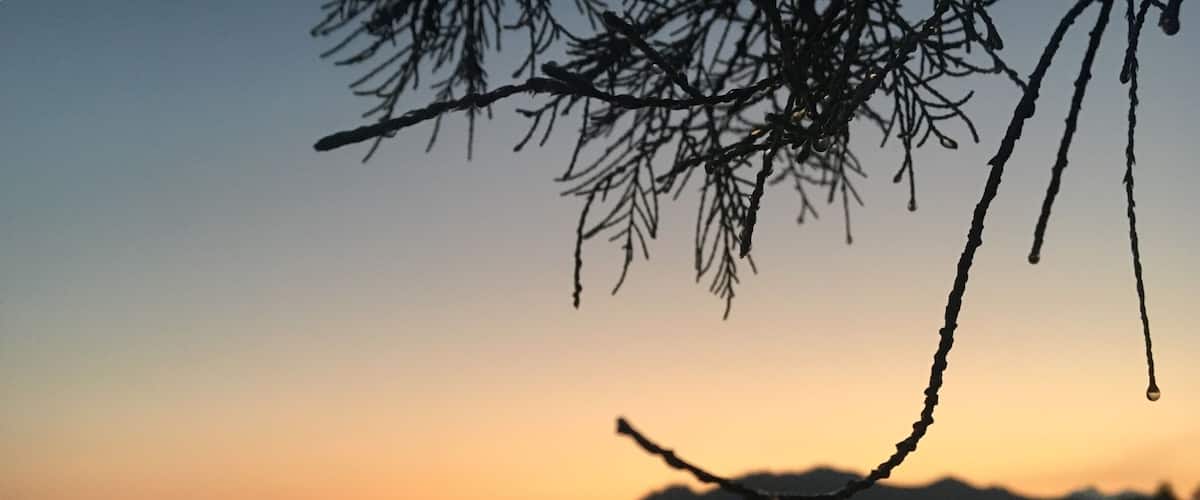 A sunset over a beach with silhouettes of mountains in the background.