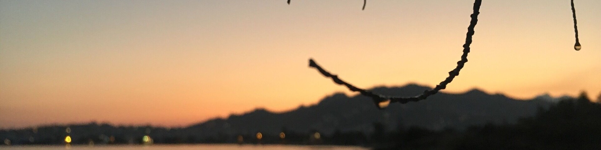 A sunset over a beach with silhouettes of mountains in the background.