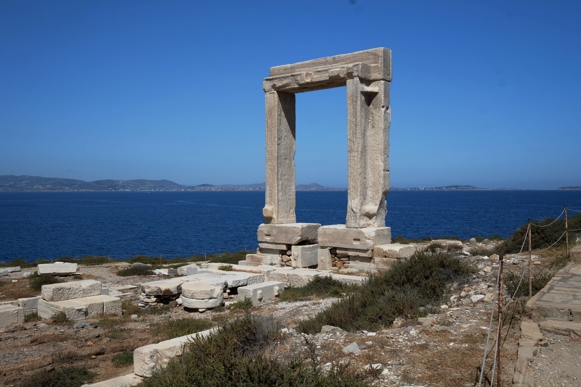 The Portara stands on Palatia, which was once a hill but is now a separate little island connected to Naxos by a causeway. 

The Portara is the entrance to an unfinished temple that faces directly toward Delos, Apollo's birthplace. For this reason most scholars believe it was dedicated to Apollo, but some think it was built in honor of Dionysus, who was worshipped on Naxos Island.