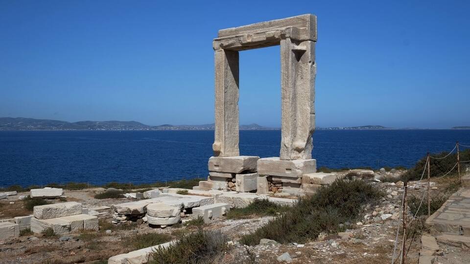Vestiges d’anciens bâtiments en pierre offrant une vue dégagée sur la mer et les collines lointaines.