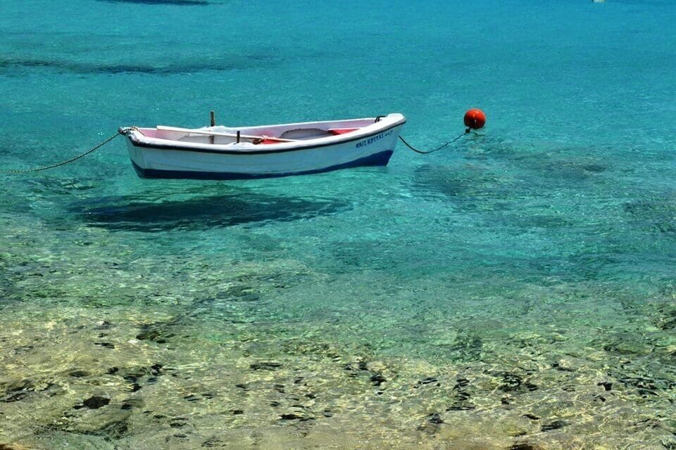 A small boat tied to a buoy in clear turquoise water.