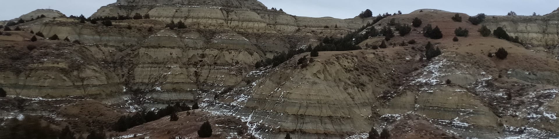 A rugged mountain landscape with layered rock formations and sparse vegetation.