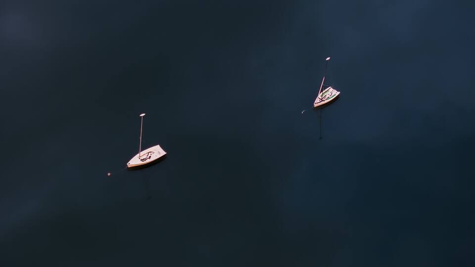 Aerial view of two sailboats floating serenely on the dark, rippled water, their white hulls contrasting against the deep blue, Boston, Massachusetts, United States.