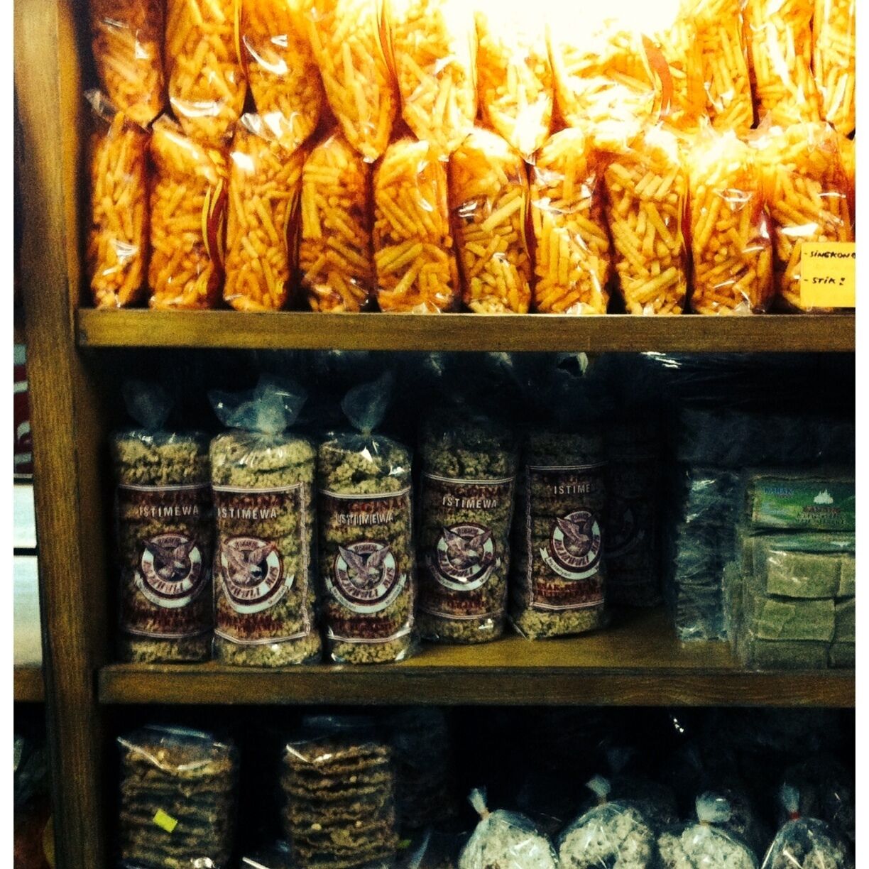 A shelf with bags of pasta and jars of spices.