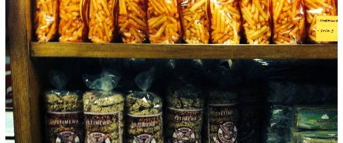 A shelf with bags of pasta and jars of spices.