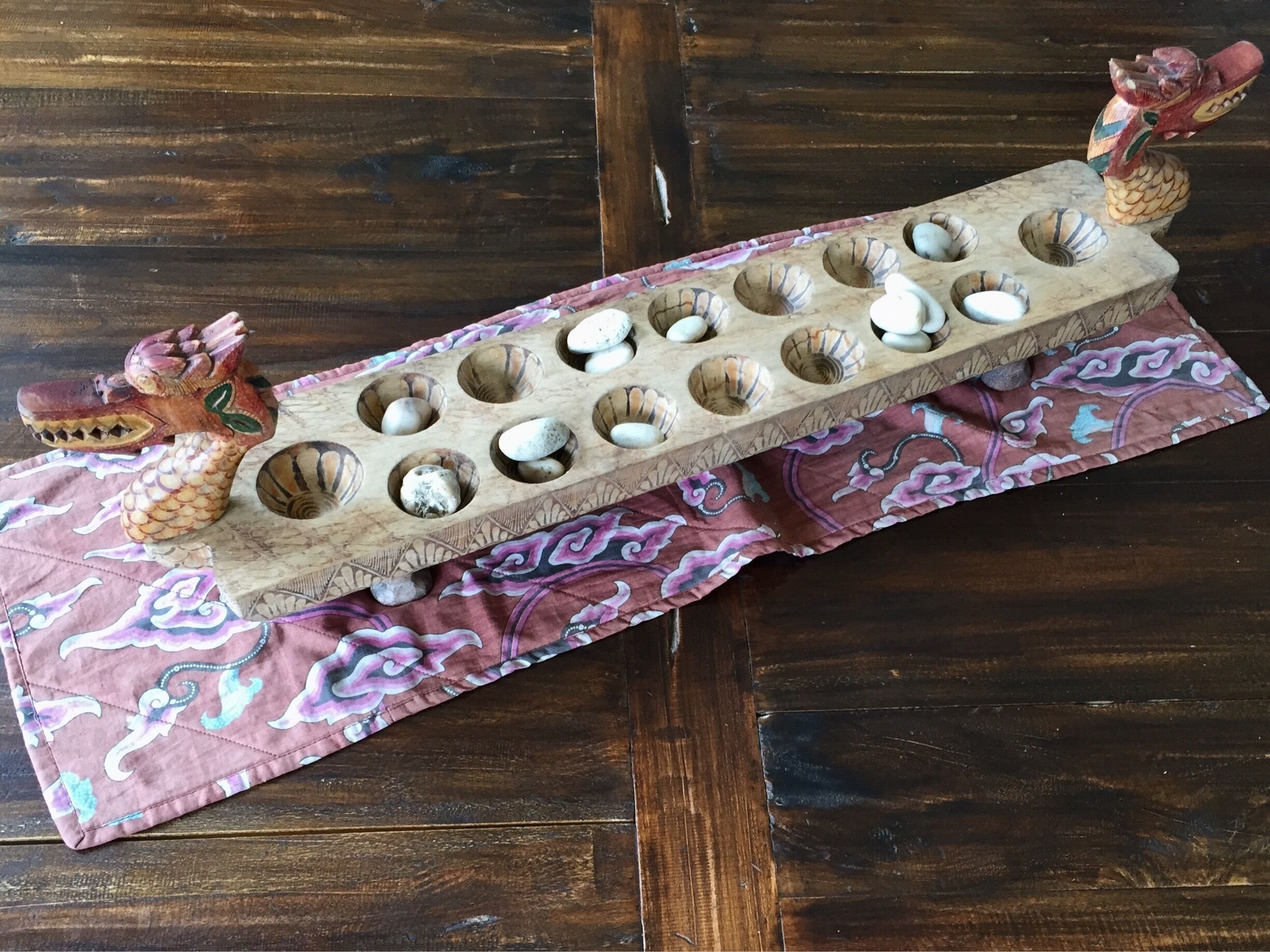 This is a traditional game which I enjoyed playing a lot as a child. Recently I found them used in hotels and restaurants in Indonesia either for decor purposes or to contain snacks. Brings back lots of good memories! It is known as Congkak in Indonesia.


The oldest mancala game boards were found in a ruined fort of Roman Egypt and date back to the 4th century AD. The game was likely introduced to Southeast Asia by Indian in the 15th century. Ancient Tamils during their Chola expedition and Trading with Indonesian Islands ( Sumetra, Java ) took this game there. In Indonesia, this is known as Congkak or Congklakin. It is believed to have spread throughout Malay world through merchants via Malacca, an important trading post at that time. In the early days, it was thought that this game was for the king and family and palace residents, however later it spread to the general population of the kingdom. Beside the Indian Peranakan also enjoy playing Congkak.

In Java, the term "dakon stone" refers to the similarly pitmarked stones from the bronze-Iron Age period of Indonesia. These stones have rows of 4 or 5 cup-shaped holes and two holes at each end, a formation which has much in common with that of the similarly named game in Java. This prehistoric dakon stones is unrelated to the game and were probably employed in ceremonies to propitiate ancestors. Such stones can be found around Java.

The current Malaysian Ringgit 10 sen coin has a Congkak board on the reverse in recognition of the long history of congkak in Malaysia.

Source: Wikipedia 