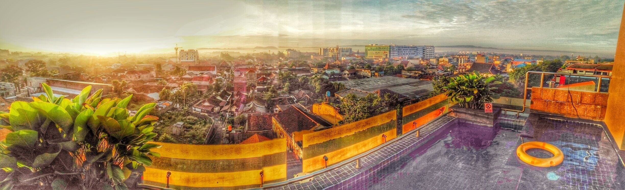 Paisagem urbana com um edifício grande, uma piscina e áreas residenciais ao redor.