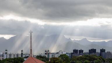 Raios de Sol passando pelas nuvens de um céu nublado em um dia chuvoso. Igreja em primeiro plano.