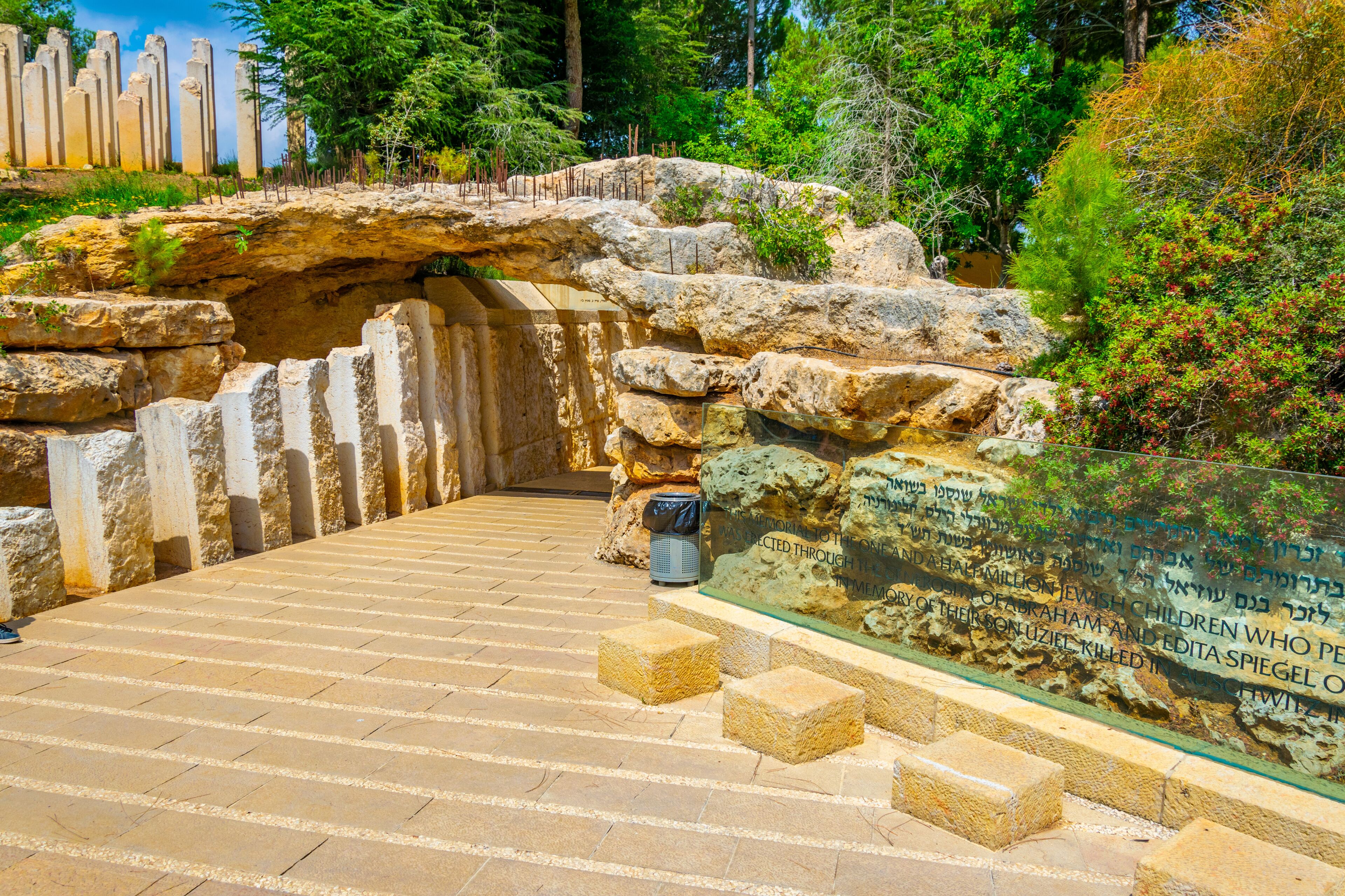 Caminho de pedra que leva a um sítio histórico, com inscrições e uma vitrine de vidro.