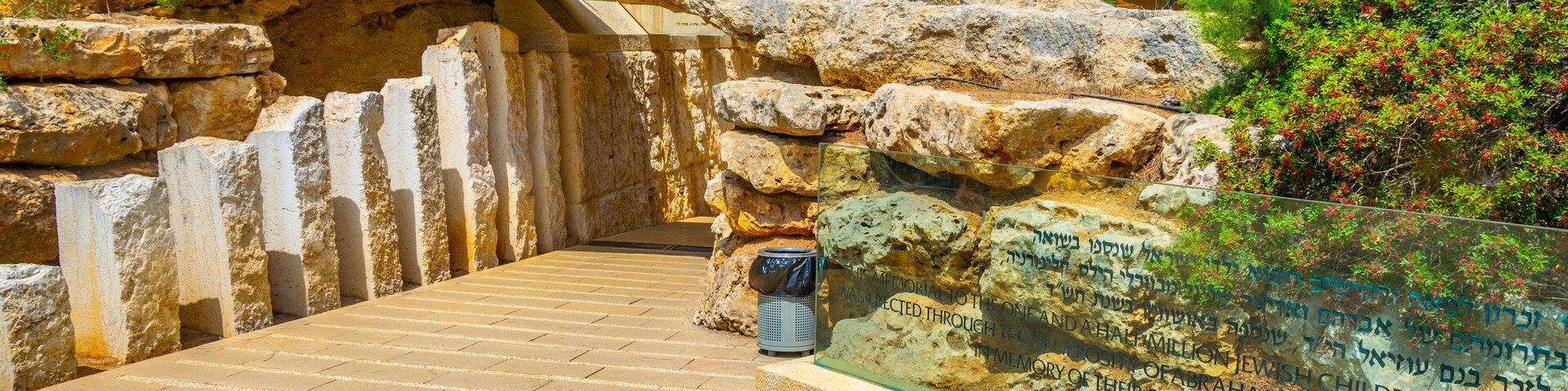 Caminho de pedra que leva a um sítio histórico, com inscrições e uma vitrine de vidro.